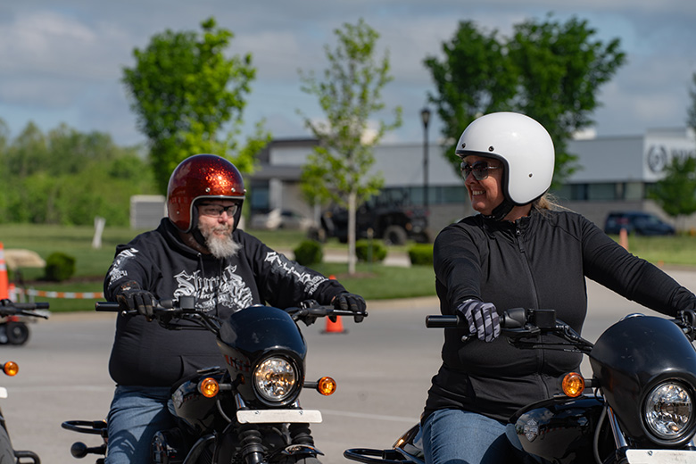 Two people driving motorcycles through a training course.
